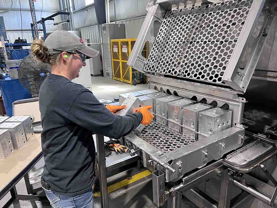 ManifoldWash Thermal deburring causes surface oxidation on the smallest scale. Here an employee puts parts through a washer to combat the surface oxidation after processing.